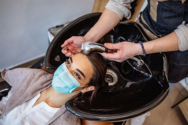 Мытье головы клиента в парикмахерской мойке